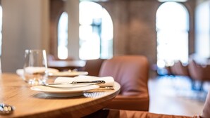 A dining table with plates, cutlery, and a glass, set in a restaurant with a modern interior and large windows. - Hotel Breitenburg (Breitenburg)