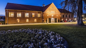A large brick building with a sloped roof, large windows, and a sign reading "HC GR & EGR". - Hotel Breitenburg (Breitenburg)