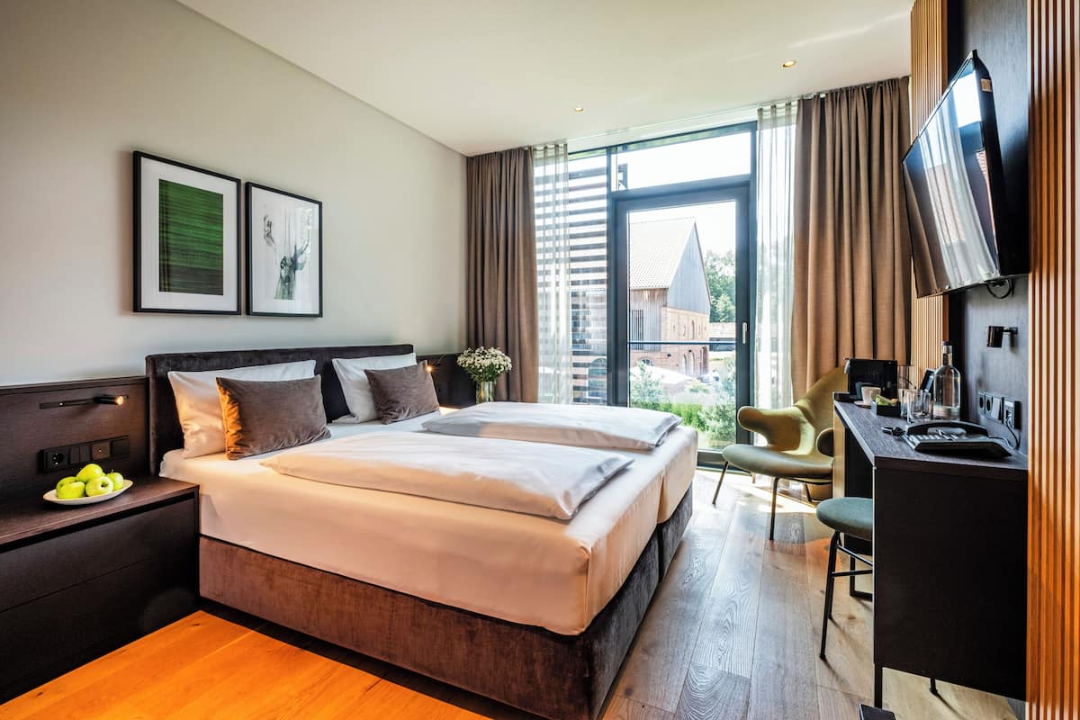 A modern hotel room with a large bed, a desk, and a TV.