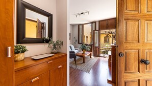 Un intérieur en bois agrémenté d’un miroir, d’un vase avec des plantes, d’un canapé et d’une table à manger.