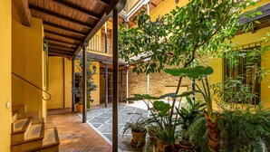 Un espace extérieur abrité, doté d’un sol carrelé, de plantes en pot et d’un escalier menant à un niveau supérieur.