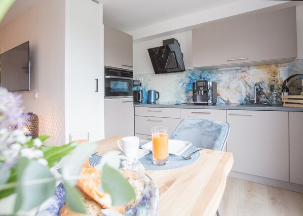 A modern kitchen with a flat-screen TV, a coffee machine, and a microwave. - Ferienwohnung Schöne Aussicht (Winterberg)