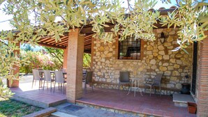 An outdoor patio with stone walls, a pergola, and outdoor seating.