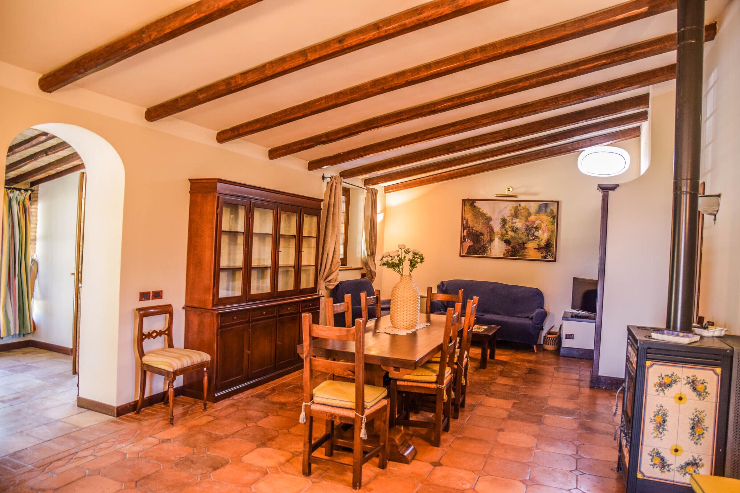 Un coin repas avec une table et des chaises en bois, un buffet, un canapé et un tableau accroché au mur.