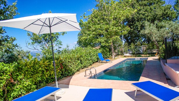 A pool area with blue lounge chairs and a white umbrella.