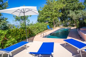 A pool area with blue lounge chairs and a white umbrella. - Casa con giardino/piscina privati vicino a Orvieto (Umbria)