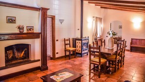 A dining area with a fireplace, wooden furniture, and a tiled floor.