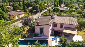 A residential area with a house featuring a tiled roof, a swimming pool, and a view of surrounding hills.