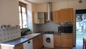 Une cuisine avec des meubles de rangement en bois, un lave-linge, une cuisinière et un four encastré.