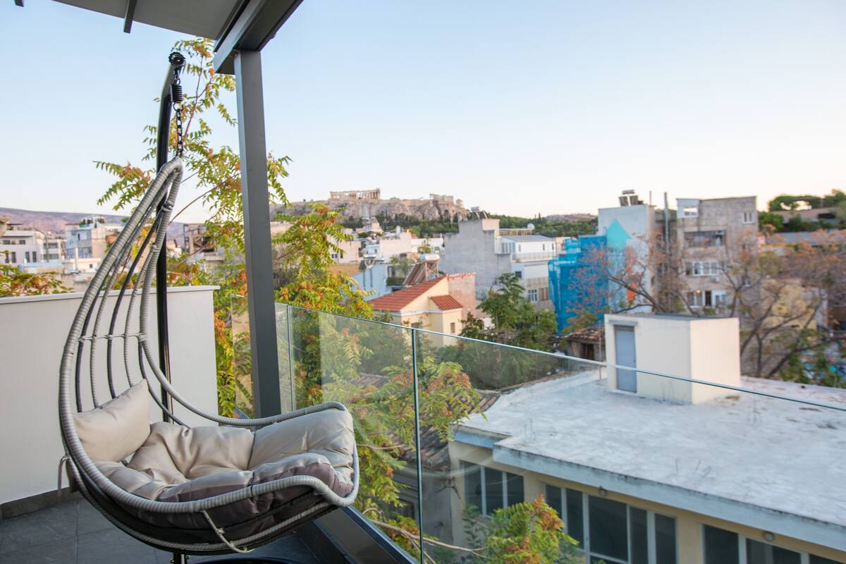 A hanging chair on a balcony with a city view.