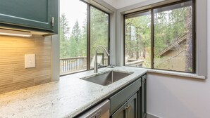 A kitchen with a granite countertop, stainless steel sink, and wooden cabinets. - Near SHARC, Hot Tub, Bikes, Dog-Friendly-LEIS03 (Sunriver)