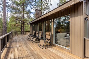 Un terrazzo in legno con posti a sedere all'aperto e ampie finestre.