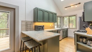 A modern kitchen with a central island, built-in appliances, and large windows. - Near SHARC, Hot Tub, Bikes, Dog-Friendly-LEIS03 (Sunriver)