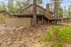 A two-story cabin with a balcony and a stone chimney. - Near SHARC, Hot Tub, Bikes, Dog-Friendly-LEIS03 (Sunriver)