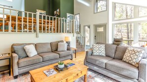 A spacious living area with two grey sofas, a wooden coffee table, and a staircase leading to an upper level. - Near SHARC, Hot Tub, Bikes, Dog-Friendly-LEIS03 (Sunriver)