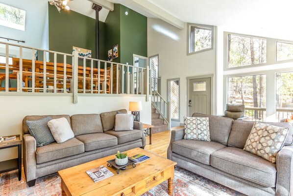 A spacious living area with two grey sofas, a wooden coffee table, and a staircase leading to an upper level. - Near SHARC, Hot Tub, Bikes, Dog-Friendly-LEIS03 (Sunriver)