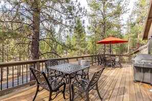 A wooden deck with a metal table and chairs, a barbecue grill, and an orange umbrella. - Near SHARC, Hot Tub, Bikes, Dog-Friendly-LEIS03 (Sunriver)