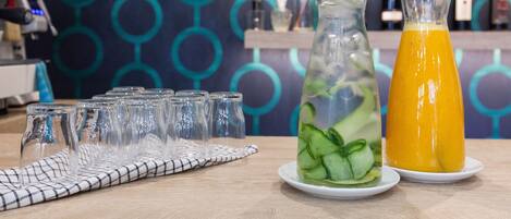 Um ambiente de bar com um jarro de vidro e uma garrafa de suco de laranja sobre um prato branco.
