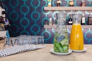A bar setting with a clear glass pitcher and a bottle of orange juice on a white plate.