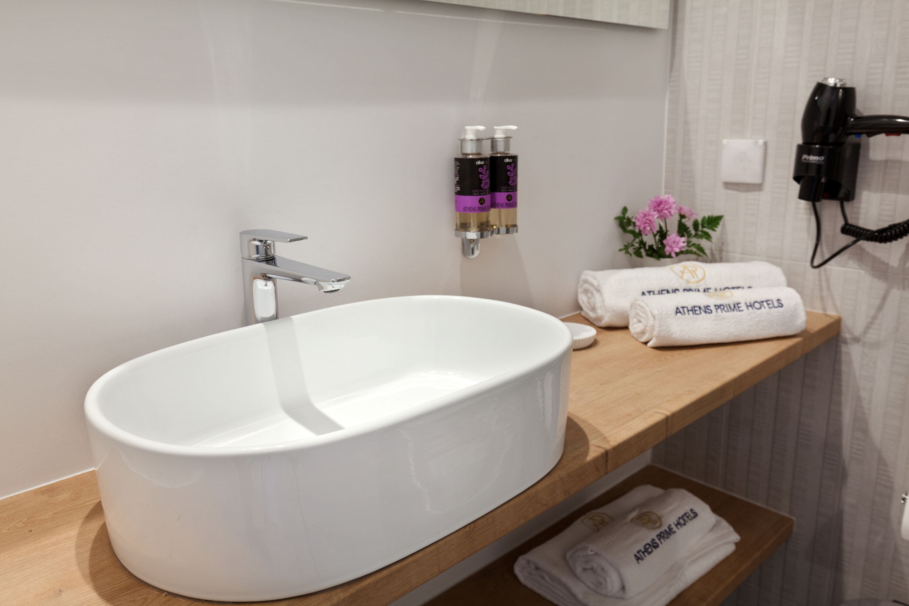 A modern bathroom with a large white sink, a wooden vanity, and toiletries on the wall.