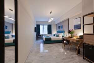 Quarto de hotel moderno com cama, escrivaninha, cadeira e um pequeno armário.