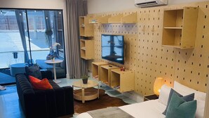 Ein modernes Hotelzimmer mit einem großen Bett, einer Couch, einem Fernseher und eingebauten Regalen.