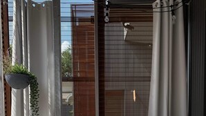 Ein moderner Außenbereich zum Sitzen mit einer Couch, bunten Kissen und einem runden Tisch mit einer Pflanze.