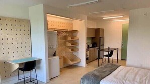 A compact hotel room with a bed, a desk, and a kitchenette. - Bardo Loft Suite #201 (Dallas)