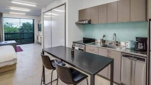 A modern kitchen with a dining area, featuring a stove, sink, and cabinets. - Bardo Loft Suite #201 (Dallas)