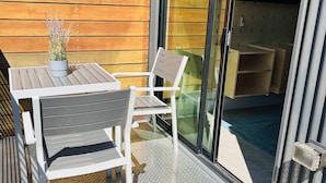 Een terras met een tafel en stoelen, een plant in pot en een schuifdeur naar een binnenruimte.