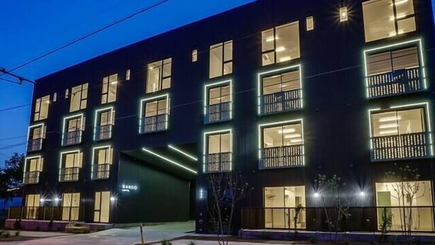 Een modern gebouw met meerdere balkons en grote ramen, met een 'BARDO' bord.
