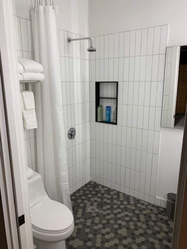 A bathroom with a toilet, shower, and tiled walls.