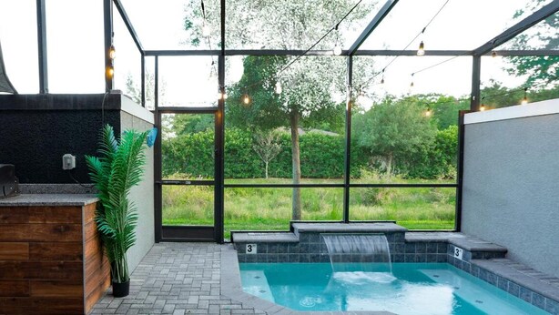 An outdoor patio with a barbecue grill, a small hot tub, and a view of a lush garden. - Disney-Themed Escape – Frozen & Star Wars Rooms, Pool, Games & Family Fun (Kissimmee)