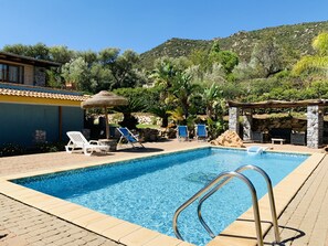 A swimming pool with lounge chairs and a stone wall.