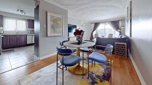 A modern living room with a round table, blue chairs, a sofa, and a decorative vase. - CHARMING THREE BEDROOM FLAT (brampton)