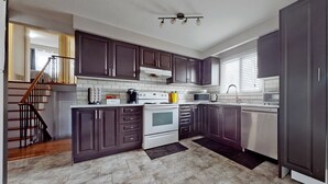 A modern kitchen with dark cabinets, a white stove, a microwave, and a dishwasher. - CHARMING THREE BEDROOM FLAT (brampton)
