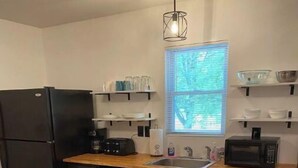 A kitchen with a wooden countertop, a bowl of bananas, a refrigerator, a microwave, and shelves with dishes. - Heart and soul on Windrock (Oliver Springs)