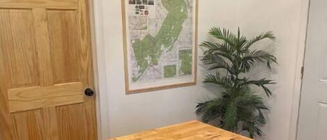 A kitchen with a wooden countertop, a bowl of bananas, a map on the wall, and a potted plant.