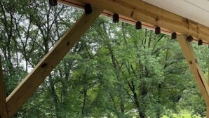 A wooden deck with a metal fence overlooking a gravel road and trees. - Heart and soul on Windrock (Oliver Springs)