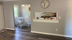 Une cuisine moderne avec une horloge, des armoires blanches et un plan de travail agrémenté de plantes en pot.