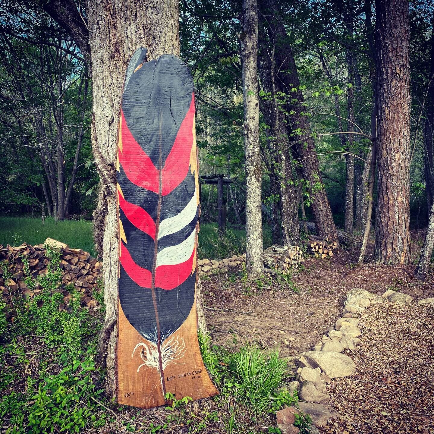 A wooden structure with a painted design in a forest setting.