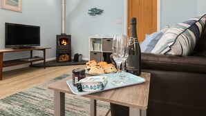 A cozy living room with a fireplace, a television, a sofa, and a table with snacks and drinks.