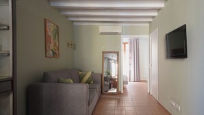 Una sala de estar con un sofá gris, un televisor de pantalla plana y un cuadro en la pared.