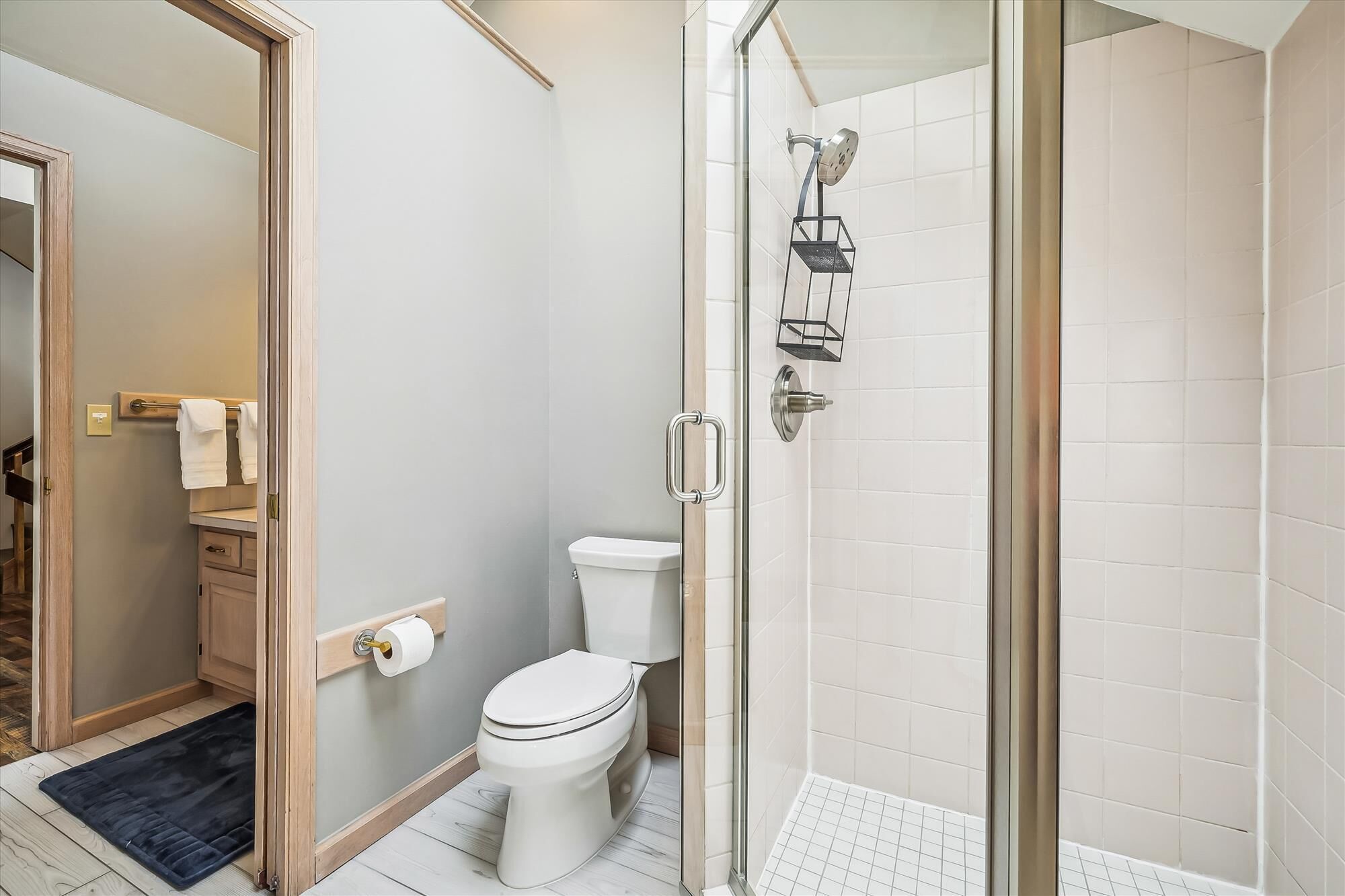 Un baño con inodoro, cabina de ducha de vidrio y perchero para toallas.