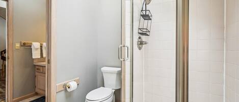Un baño con inodoro, cabina de ducha de vidrio y perchero para toallas.