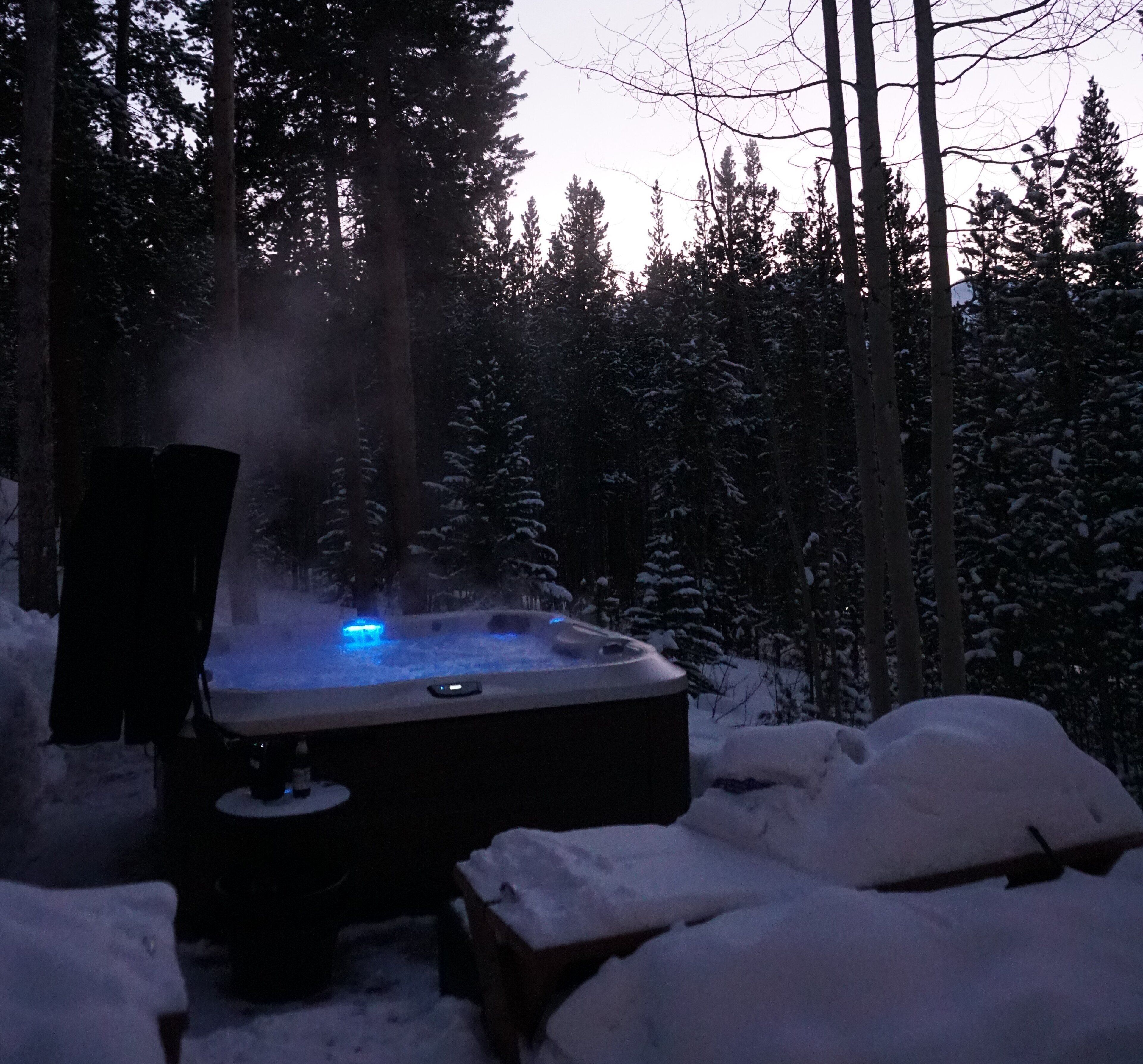 Un bain à remous entouré de neige, au cœur d’une forêt.