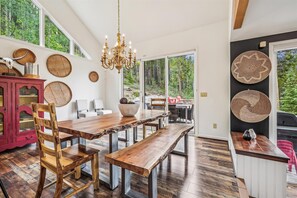 A dining area with a wooden table, benches, and chairs. There is a chandelier above the table. - Stormbunker Paradise: Secluded Breckenridge Home Near Town (Breckenridge)