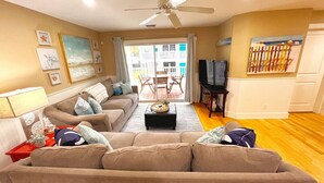 A living room with a sectional sofa, a coffee table, a TV, and artwork on the walls. - Tybee Retreat Unit 2 (Tybee Island)