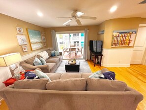 A living room with a sectional sofa, a coffee table, a TV, and artwork on the walls.