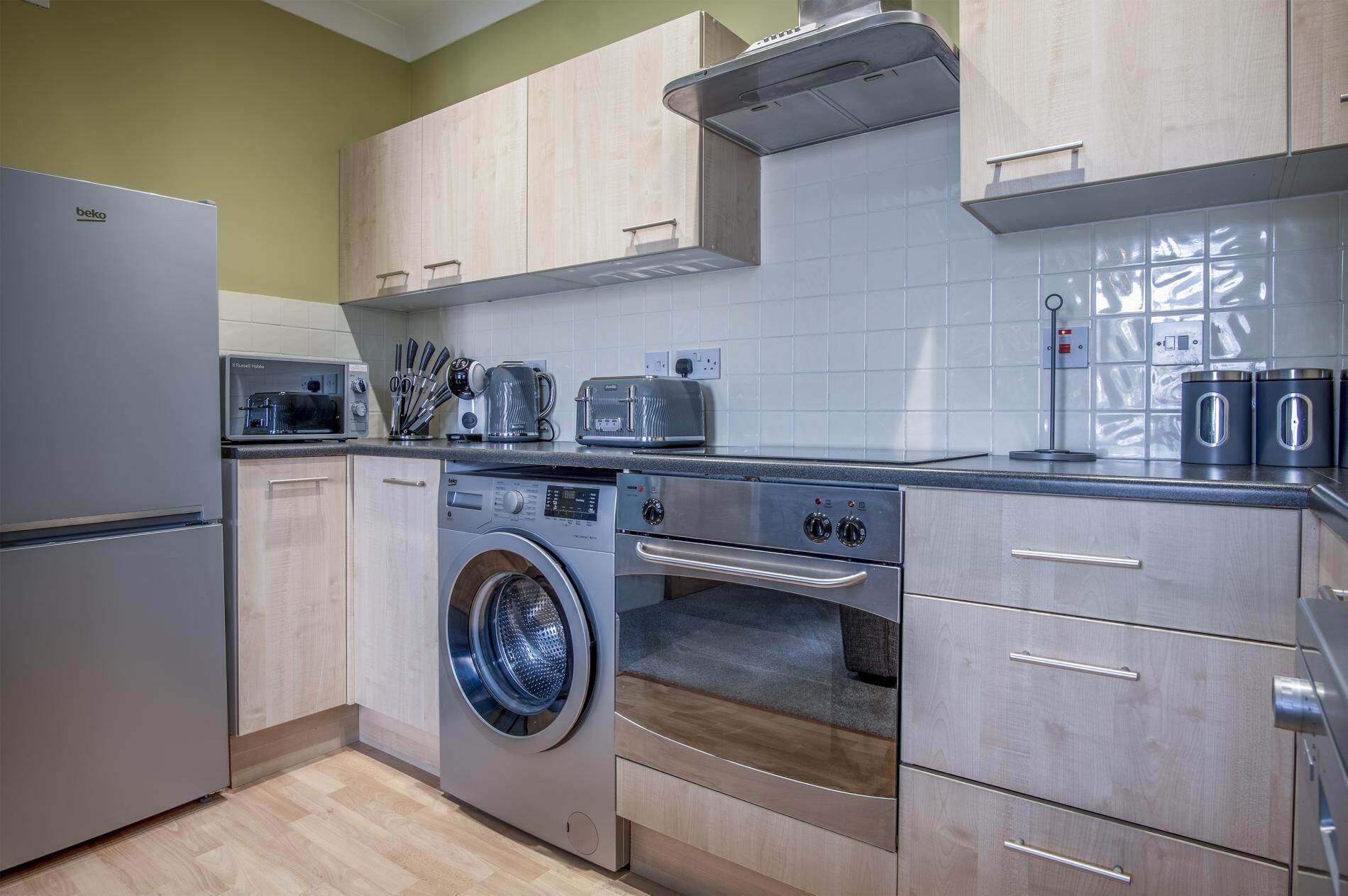A modern kitchen with a built-in washer and dryer, a refrigerator, and a toaster.